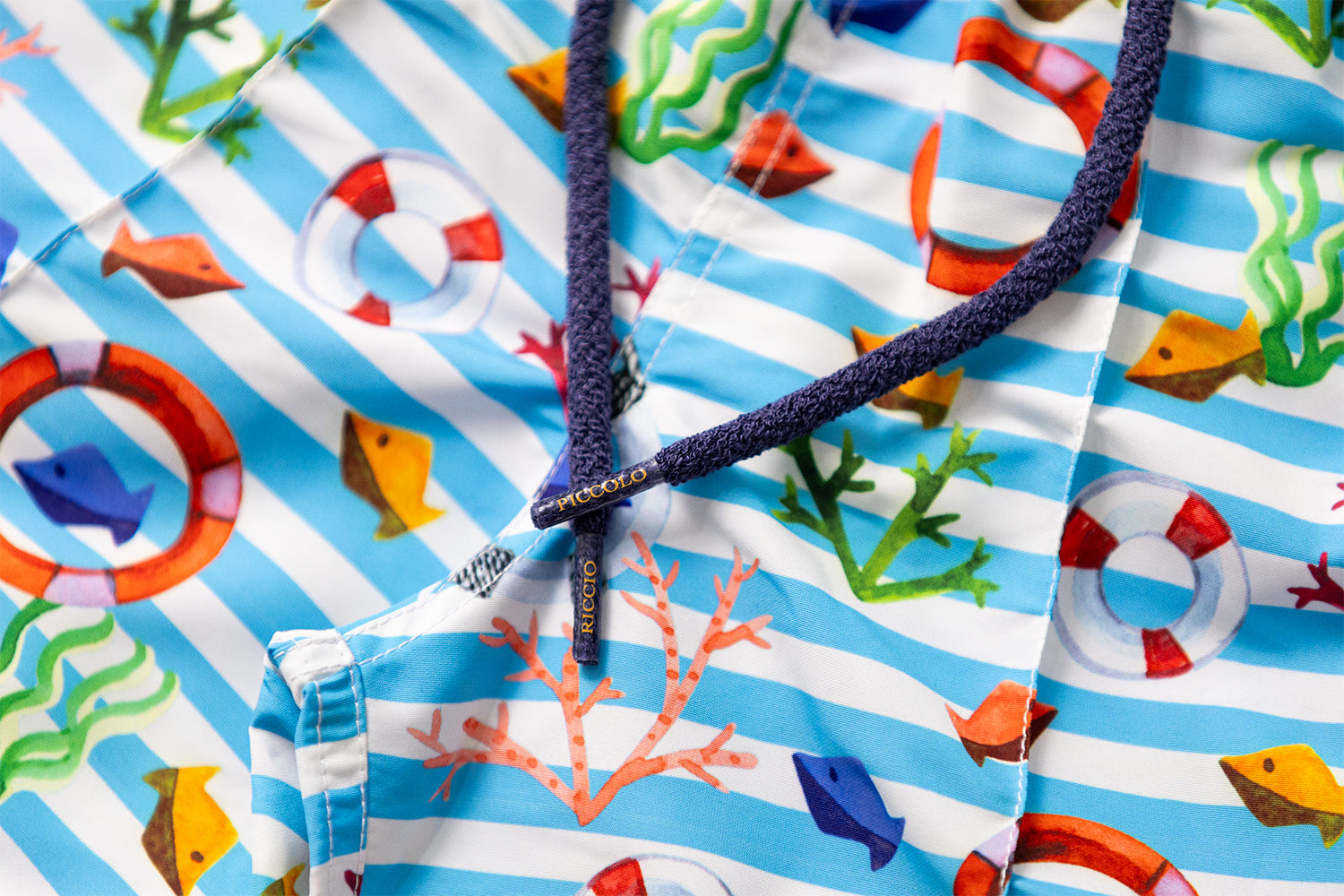 Detail of the KAI nautical motif featuring Mediterranean stripes, lifebuoys and marine elements, with signature front seam and drawstring craftsmanship by Piccolo Riccio.