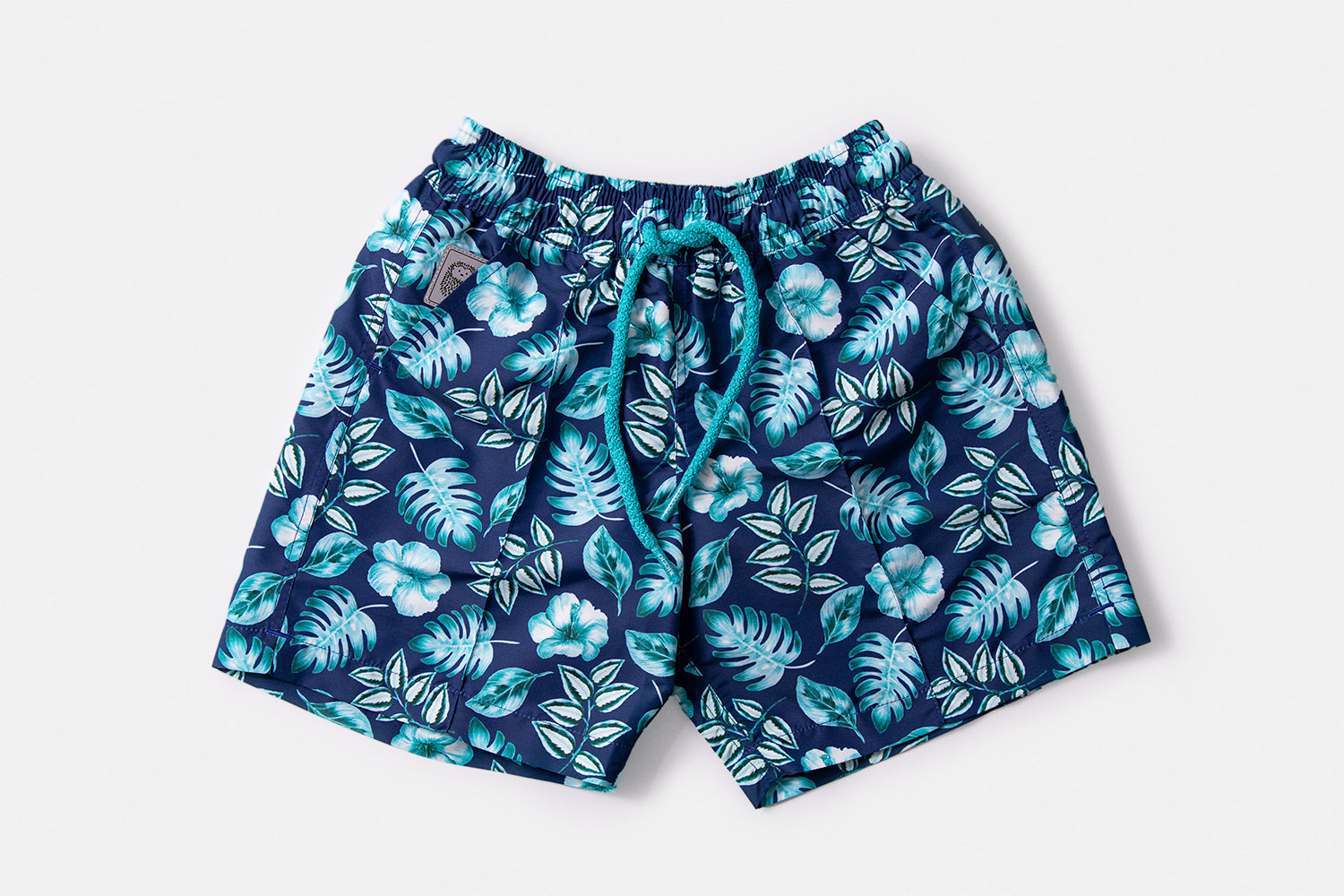 Front view of the PALAWAN Children's Edition luxury swim shorts featuring the tropical botanical motif and signature silhouette by Piccolo Riccio.