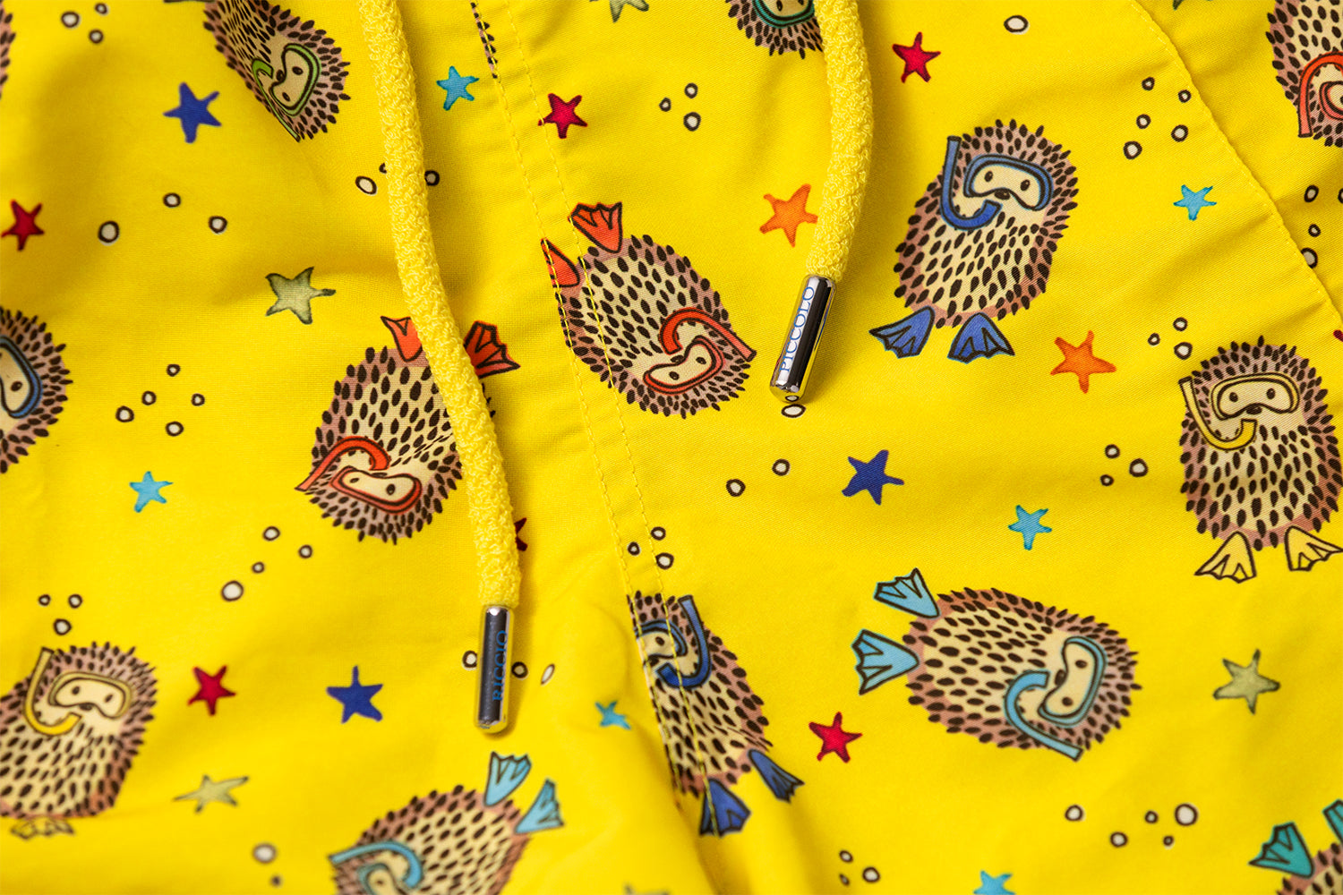 Detail of the YAKUSHIMA signature hedgehog motif, drawstring craftsmanship and distinctive front seam inspired by 1960s Riviera tailoring by Piccolo Riccio.